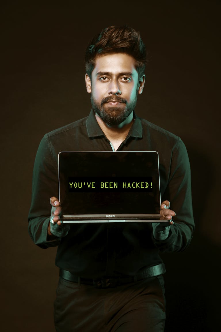 A man showing a laptop with a 'You've been hacked' message, symbolizing cyber security threats.