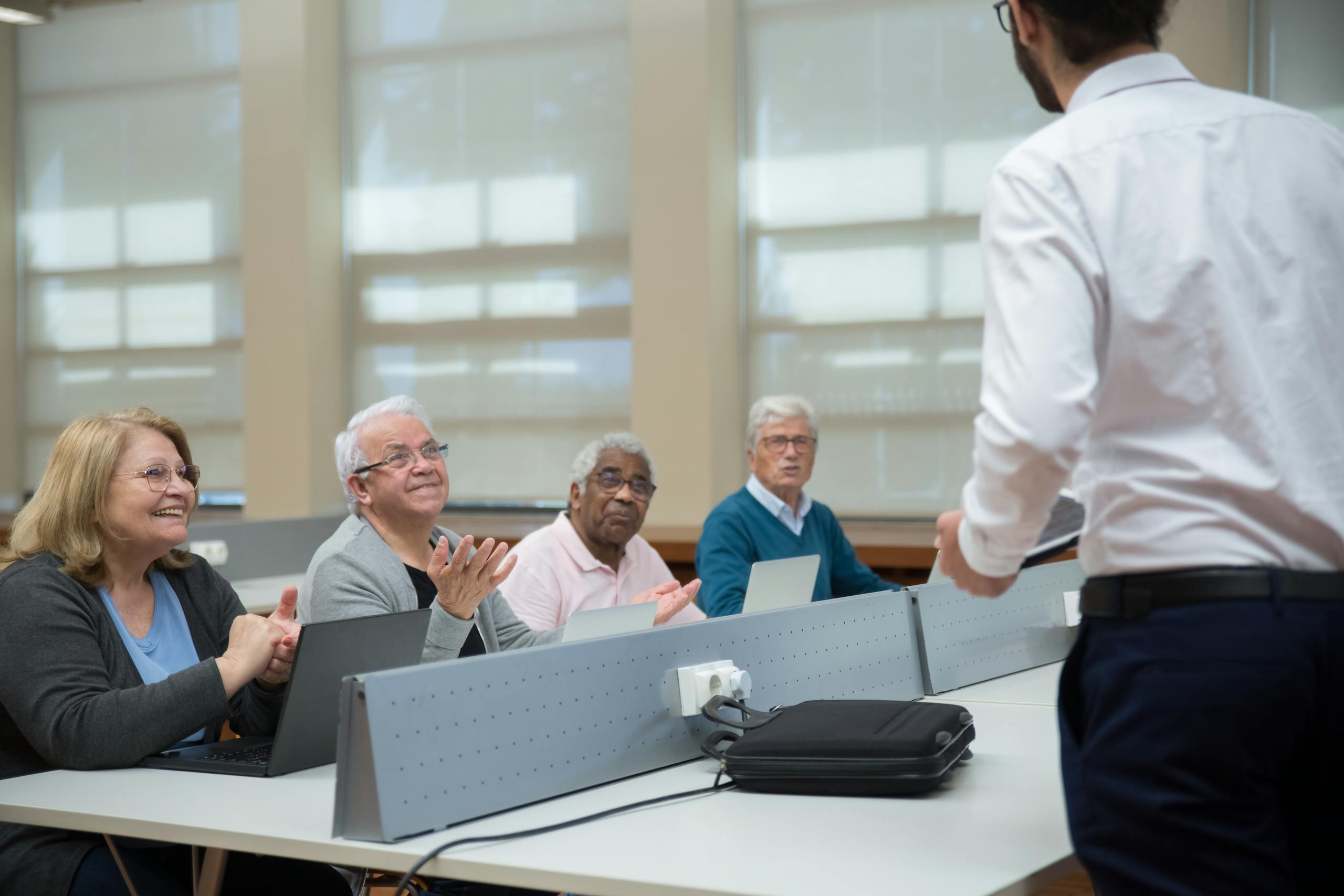 Senior adults attend a computer class, led by an instructor, in a classroom setting.